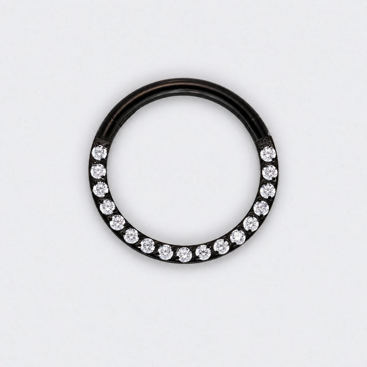 A black metal ring featuring a row of clear round-cut gemstones along the lower half, photographed against a plain white background.