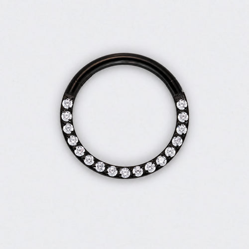 A black metal ring featuring a row of clear round-cut gemstones along the lower half, photographed against a plain white background.