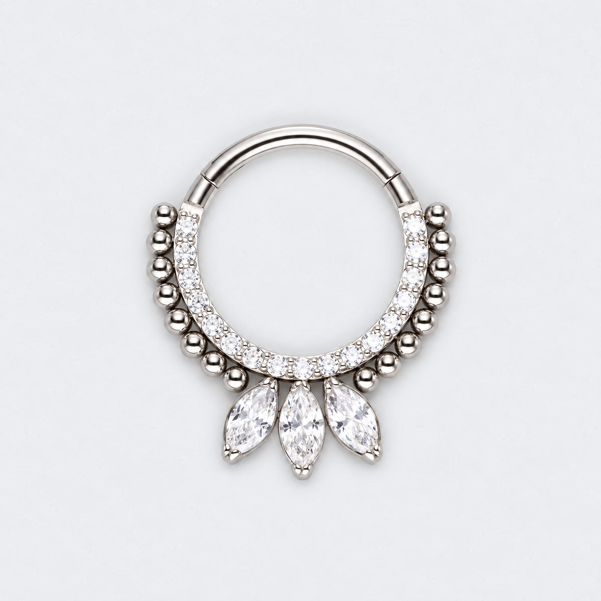A silver-toned hoop piercing ring decorated with small clear stones and three dangling marquise-cut clear stones, shown on a light gray background.